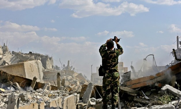 A Syrian soldier inspects the wreckage of a building described as part of the Scientific Studies and Research Centre (SSRC) compound in the Barzeh district north of Damascus, during a press tour organised by the Syrian government after US-led strikes - AF