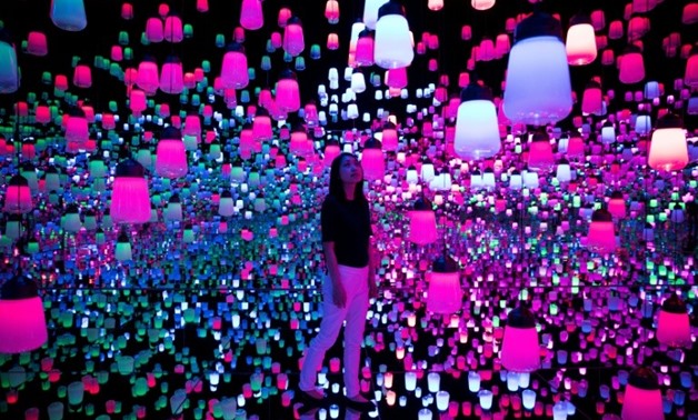 A member of the teamLab collective walks through a digital installation room in Tokyo featuring hanging lamps that light up as the visitor nears-AFP / Behrouz MEHRI

