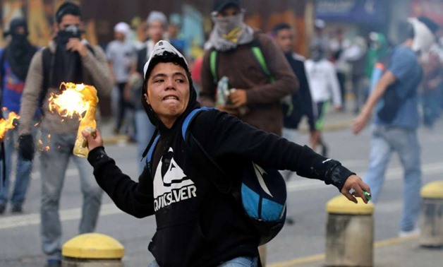 A demonstrator throws a molotov cocktail while clashing with riot police during a rally against Venezuela's President Nicolas Maduro's government in Caracas on Monday. Photo: Reuters