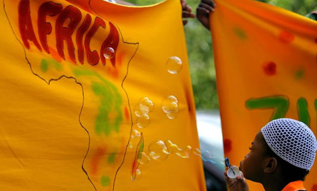 A child blows soap bubbles on a banner picturing the African continent during celebrations of Africa
