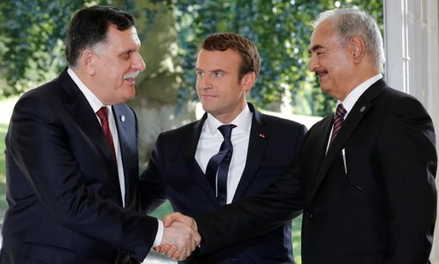 French President Emmanuel Macron stands between Libyan Prime Minister Fayez al-Sarraj (L), and General Khalifa Haftar (R), commander in the Libyan National Army (LNA), who shake hands after talks over a political deal to help end Libya’s crisis in La Cell