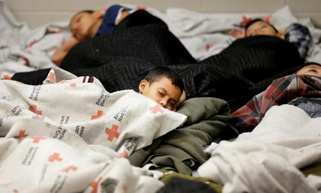 FILE PHOTO: Detainees sleep in a holding cell at a U.S. Customs and Border Protection processing facility, in Brownsville, Texas June 18, 2014. REUTERS/Eric Gay/Pool