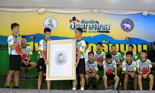 Boys who were rescued from a flooded cave hold a portrait of the former Navy SEAL diver Saman Kunan who died during the rescue operation as they pay their respect during a news conference in the northern province of Chiang Rai, Thailand, July 18, 2018. RE
