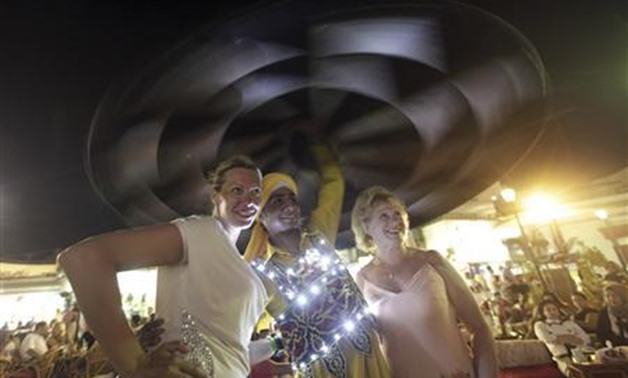 Tourists pose with a performer during a traditional Sufi dance show, which is part of the Badium Sinai Arabic concert, in the Red Sea resort of Sharm el-Sheikh, south of Cairo in this July 12, 2012 file photo. REUTERS/Amr Abdallah Dalsh/Files