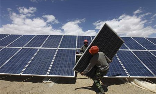 Workers install a solar panel in Jiuquan, Gansu province, in this July 14, 2013 file photo. REUTERS/Stringer/Files