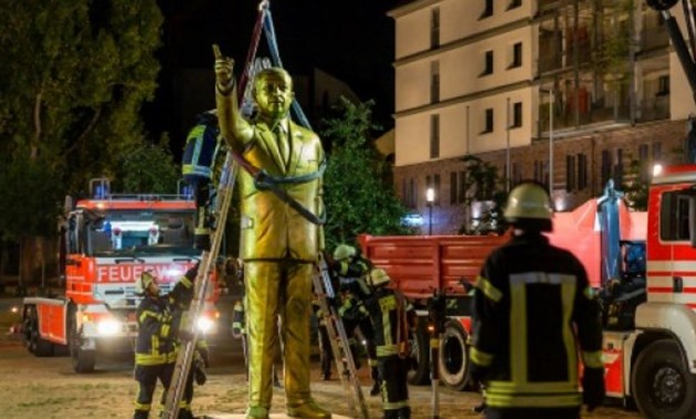 Firefighters use a crane to remove a four-metre golden statue of Turkish President Recep Tayyip Erdogan from a town square in the German city of Wiesbaden - AFP