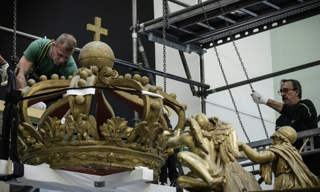 Workers removing the ornate crown atop Napoleon Bonapart's imperial canoe at France's National Naval Museum in Paris on Tuesday-AFP / Philippe LOPEZ


