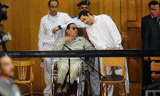 FILE-Egyptian toppled president Hosni Mubarak and his two sons Alaa (R) and Gamal stand behind bars during their trial at the Police Academy on September 14, 2013 in Cairo. AFP PHOTO / AHMED EL-MALKY