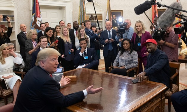 US President Donald Trump meets with rapper Kanye West (R red cap) in the Oval Office of the White House in Washington, DC, on October 11, 2018.
