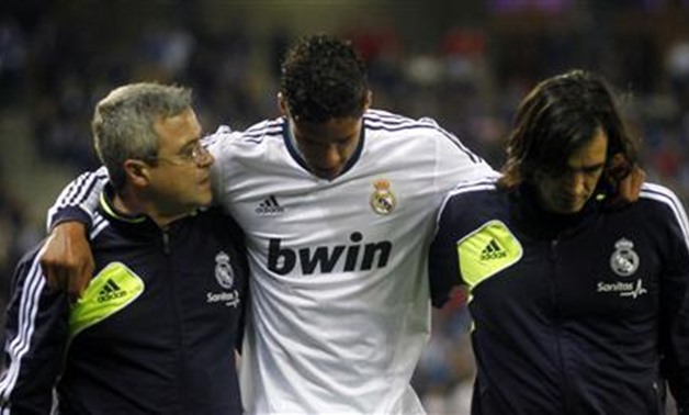 Real Madrid's Raphael Varane (C) leaves the pitch injured, helped by medical staff, during their Spanish First division soccer league match against Espanyol at Cornella-El Prat stadium, near Barcelona May 11, 2013. REUTERS/Albert Gea
