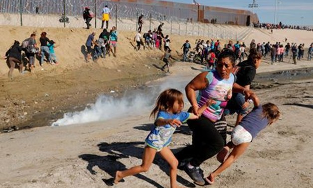 Maria Lila Meza Castro (C), a 39-year-old migrant woman from Honduras, part of a caravan of thousands from Central America trying to reach the United States, runs away from tear gas with her five-year-old twin daughters Saira Nalleli Mejia Meza (L) and Ch