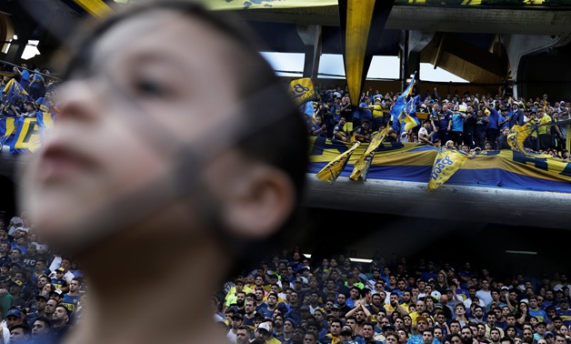 A boy and soccer fans of Boca Juniors cheer during the match between Boca Juniors and Patronato, ahead of the second leg of the final of the Copa Libertadores between local rivals Boca Juniors and River Plate in Buenos Aires, Argentina, November 17, 2018.