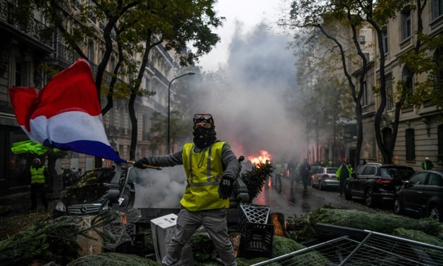 A protester waves the French flag over a barricade made of christmas trees during the "yellow vest" protests in Paris on Saturday

