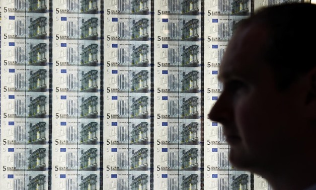 FILE PHOTO: A man is seen in front of a sheet of five Euro notes at the opening of the new Central Bank of Ireland offices in Dublin, Ireland April 24, 2017. REUTERS/Clodagh Kilcoyne
