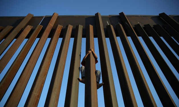 A child climbs up the Mexican side of the US-Mexico border fence at Sunland Park, New Mexico, in June 2018
