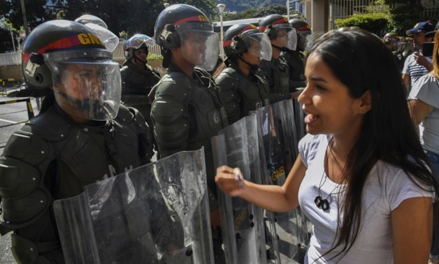 Members of the Bolivarian National Guard stand guard near the main entrance of the forces' headquarters in Caracas as Guaido supporters distribute copies of their anti-Maduro amnesty tracts
