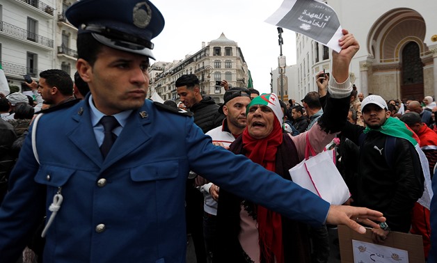 A police officer stands guard as people protest against Algeria's President Abdelaziz Bouteflika, in Algiers, Algeria March 8, 2019. The sign reads: "No to the fifth term." REUTERS/Zohra Bensemra
