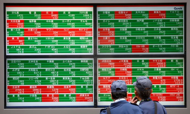 Reuters. FILE PHOTO: Men look at stock quotation boards outside a brokerage in