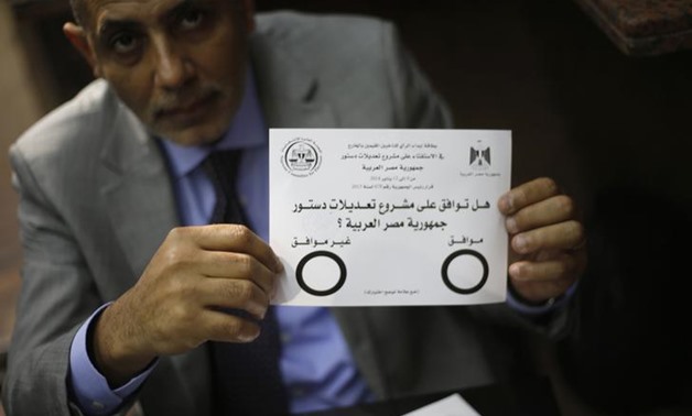 FILE - An Egyptian man displays the voting paper that says "Do you approve the constitutional amendments?" during the referendum on the new constitution at the Egypt Consulate abroad, 2014 - Reuters