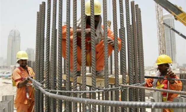 File photo of workers fixing a bridge pillar on a road construction site in Dubai, June 21, 2006. Beyond the gleaming towers, busy highways and luxury villas of Dubai, hundreds of thousands of South Asian labourers who helped build them live in cramped an
