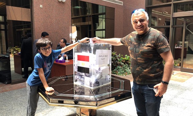 An Egyptian expat with his son casts his vote on the constitutional amendments at the embassy of Dubai- Press photo