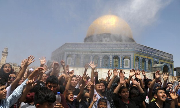 Palestinian men spray water on children to cool them down before prayers on the last Friday of the holy month of Ramadan near the Dome of the Rock, in the compound known to Muslims as Noble Sanctuary and to Jews as Temple Mount, in Jerusalem's Old City, M