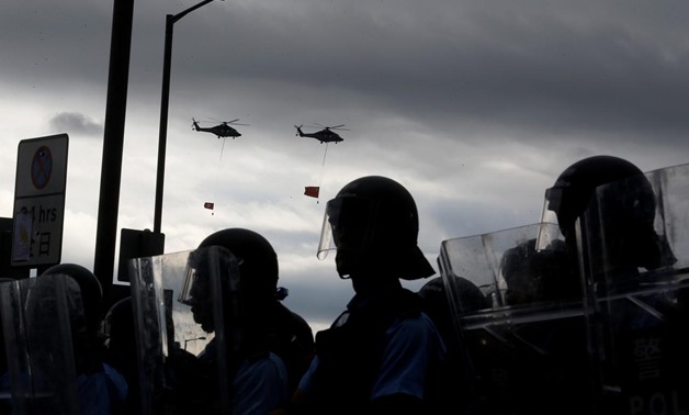 Helicopters fly the national flags of Hong Kong and China above riot police and protesters during the anniversary of Hong Kong's handover to China in Hong Kong, China July 1, 2019. REUTERS/Thomas Peter
