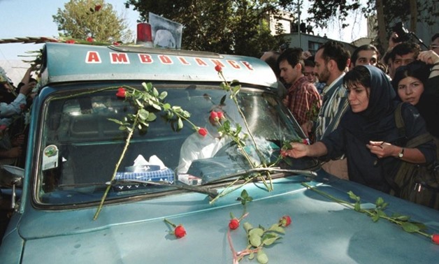 An Iranian mourner layes red roses on the ambulance that carries the coffin of Iranian poet Ahmad Shamlou during his funeral in Tehran 27 July 2000 (AFP)