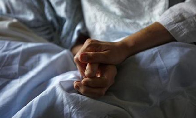 A woman holds the hand of her mother who is dying from cancer during her final hours at a palliative care hospital in Winnipeg July 24, 2010. Picture taken July 24, 2010 - REUTERS