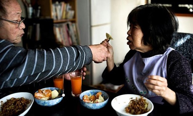 Kanemasa Ito (L) feeds his wife Kimiko at their house in Kawasaki, she was diagnosed with dementia 15 years ago and he has been caring for her - AFP
