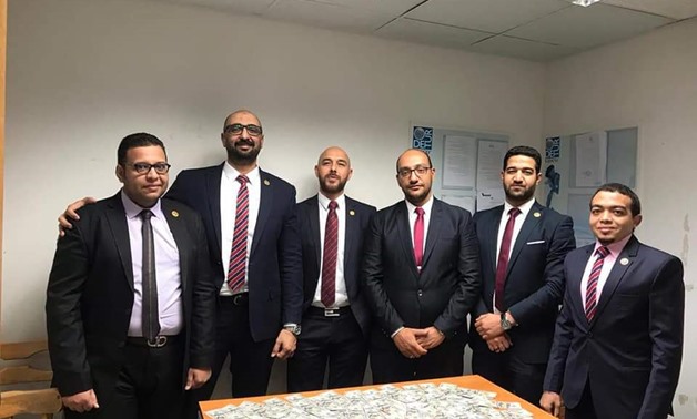 Members of customs authorities at Hurghada International Airport posing with the counterfeit dollars confiscated from an Egyptian national coming from Turkey on November 10, 2019. Egypt Today 