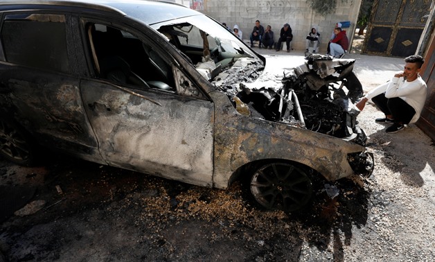 A Palestinian sits next to a vehicle that was set on fire in the southern Nablus, in the Israeli-occupied West Bank November 22, 2019. REUTERS/Mohamad Torokman
