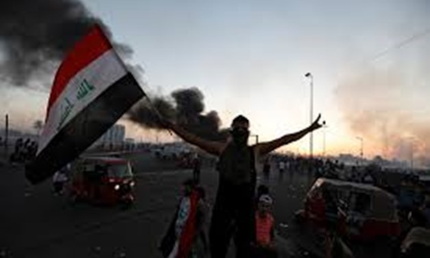 A demonstrator holds an Iraqi flag at a protest after the lifting of the curfew, following four days of nationwide anti-government protests that turned violent, in Baghdad, Iraq October 5, 2019. REUTERS/Thaier Al-Sudani
