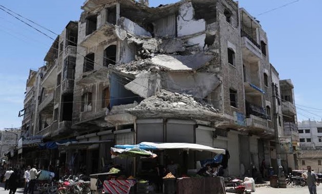 FILE PHOTO: People walk past a damaged building in the city of Idlib, Syria May 25, 2019. REUTERS/Khalil Ashawi
