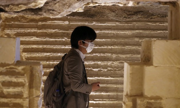 FILE- A tourist wearing a mask observes the engravings on the inner walls of the standing step pyramid of Saqqara after its renovation, south of Cairo, Egypt March 5, 2020. REUTERS/Mohamed Abd El Ghany