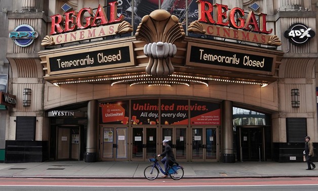 A man cycles past a shuttered movie theater in Times Square following the outbreak of coronavirus disease (COVID-19), in the Manhattan borough of New York City, New York, U.S., March 17, 2020. REUTERS/Carlo Allegri
