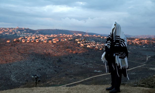 A Jewish man covered in a prayer shawl, prays in the Jewish settler outpost of Amona-  REUTERS/Baz Ratner