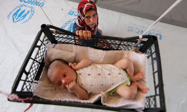 A picture from June 5, 2017 shows a displaced Iraqi girl swinging her baby brother in a makeshift hanging crib in their tent at Khazir camp between Arbil and Mosul -AFP/KARIM SAHIB