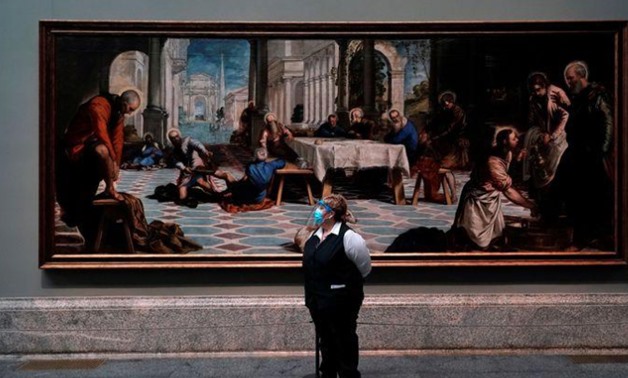 FILE PHOTO: An employee stands next to Tintoretto's painting 'Christ washing the disciples' feet' as the Prado museum reopens to public under strict social distance measures - REUTERS/Juan Medina/File Photo