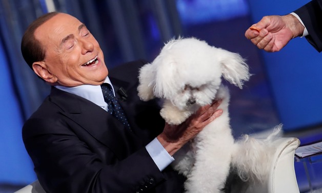 Italy's former Prime Minister Silvio Berlusconi plays with a dog during the television talk show "Porta a Porta" (Door to Door) in Rome, Italy June 21, 2017. Picture taken June 21, 2017. REUTERS/Remo Casilli