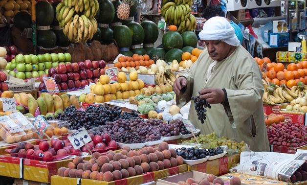 FILE - a buyer organizing the fruits in a market 
