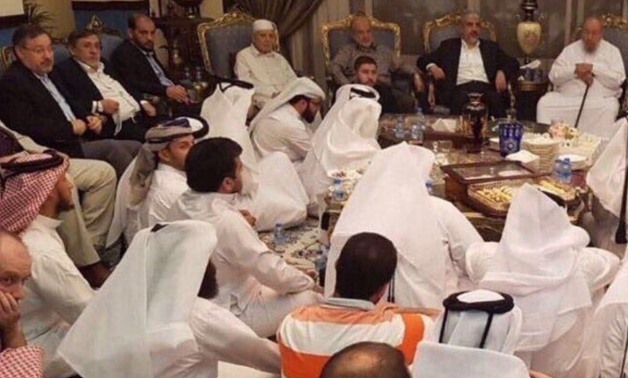 Leaders of Muslim Brotherhood and Hamas sitting ‎in chairs while a number of Qatari people are sitting on the ground at the Qatari royal palace - Twitter